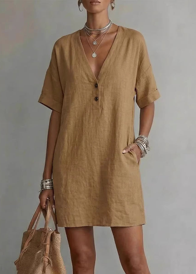 Woman wearing a brown dress holding a beige bag against a gray background