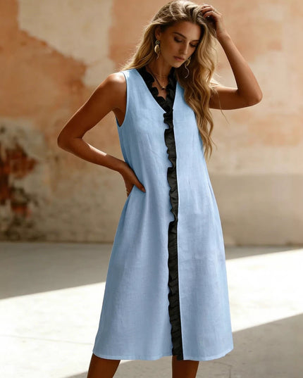 Woman wearing a light blue sleeveless dress against a textured wall.