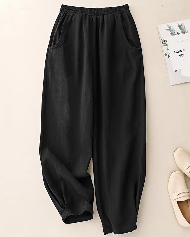 Black wide-leg pants on a light beige background with white shoes and a magazine.