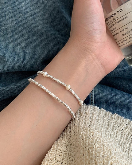 Close-up of a wrist wearing a pearl bracelet with denim fabric in the background