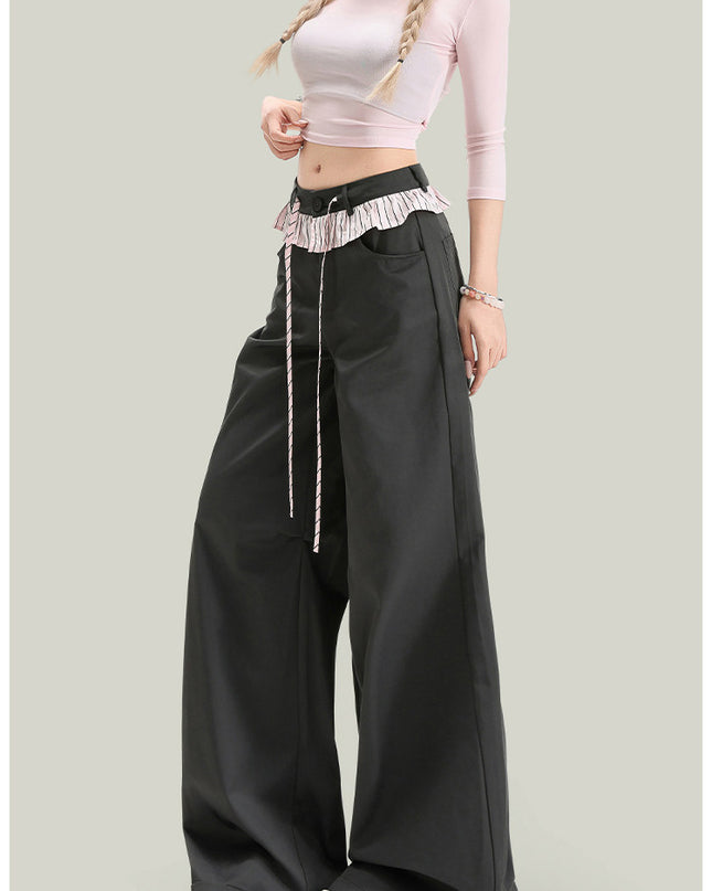 Person wearing a pink top and black wide-leg pants on a light gray background