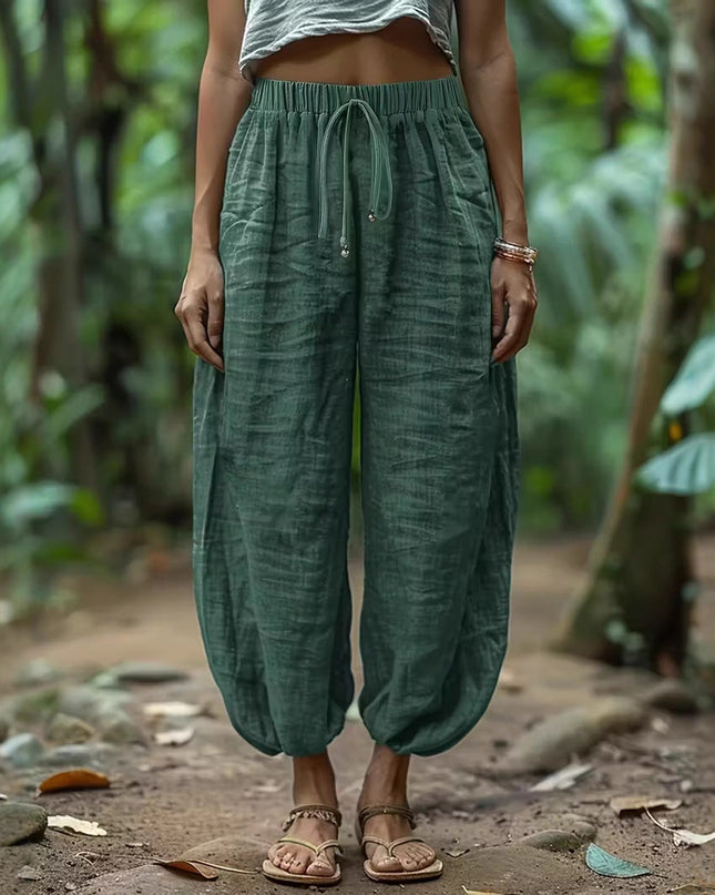 Women wearing green harem pants standing in a natural setting with greenery.