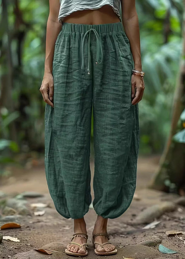 Women wearing green harem pants standing in a natural setting with greenery.