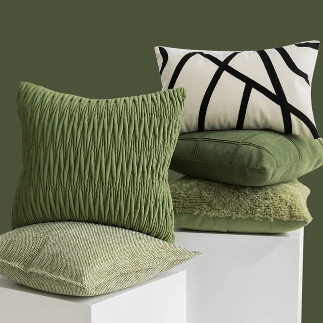 Collection of green textured pillows on a white surface with a dark green background