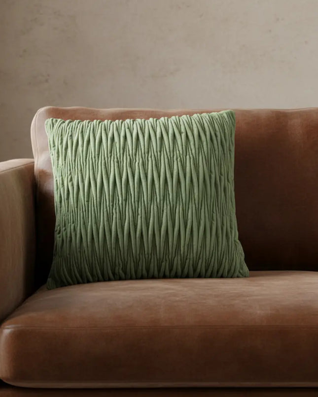 Green textured pillow on a brown sofa against a beige wall