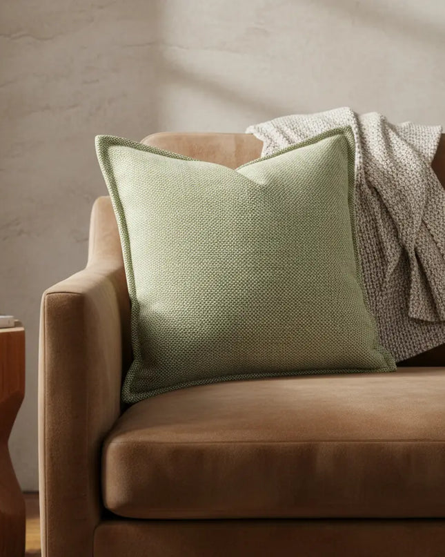 Green pillow on a brown sofa with a neutral background