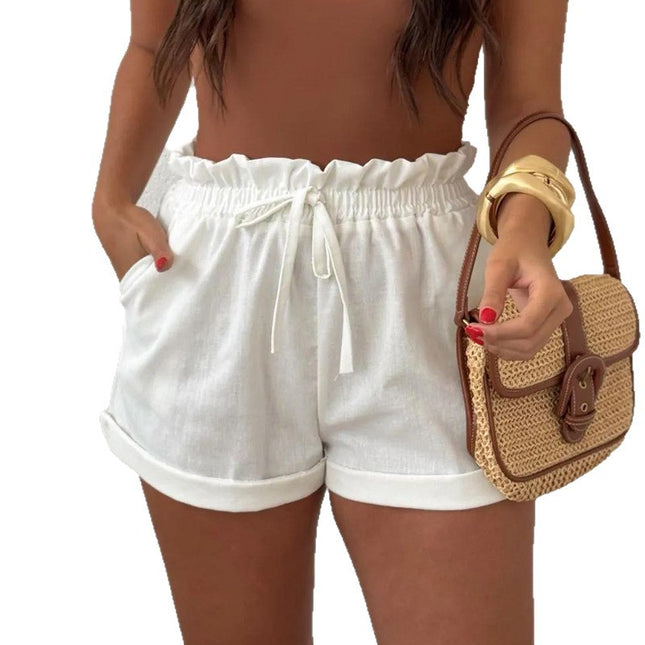 Woman wearing white shorts holding a straw bag on a white background