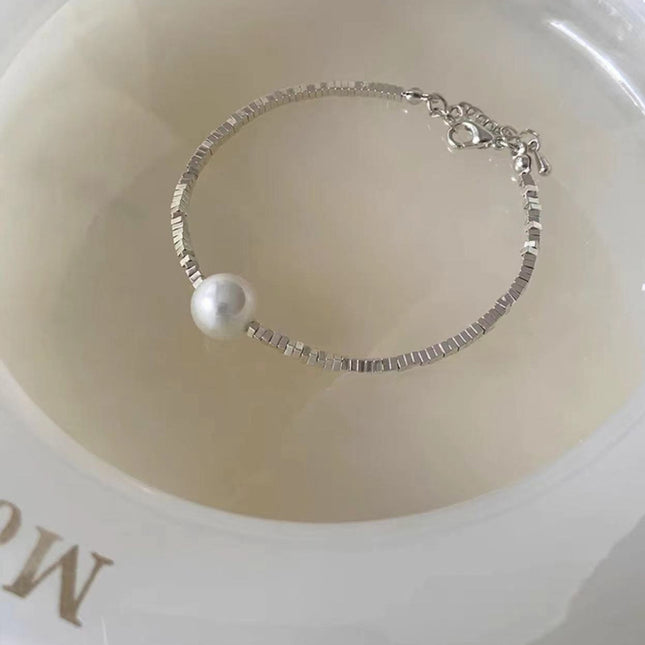 Silver bracelet with a pearl on a beige dish