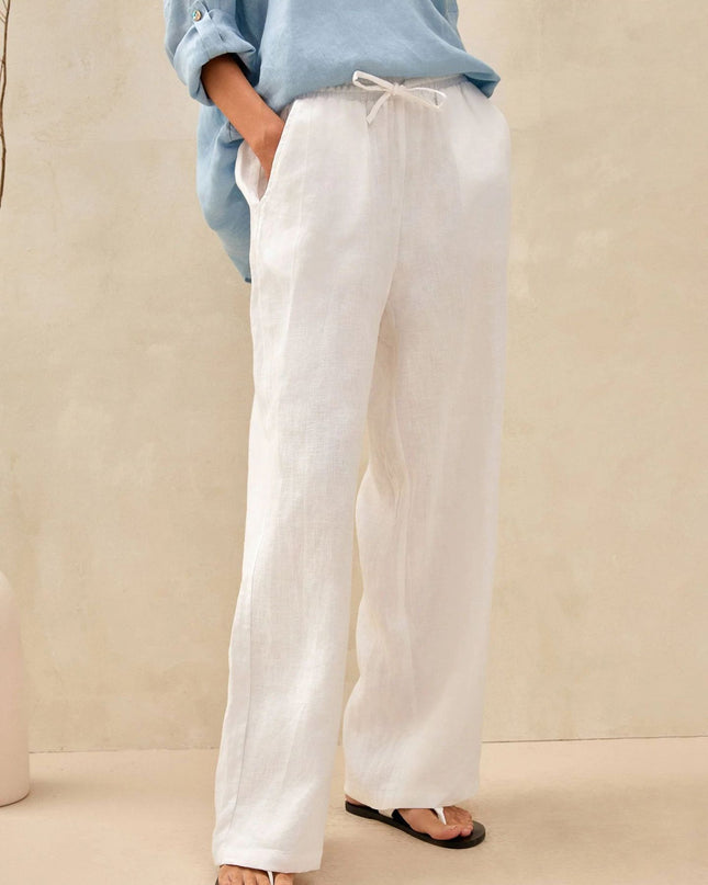 Person wearing light blue shirt and white pants on a beige background