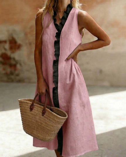 Woman wearing a pink sleeveless dress holding a straw bag against a blurred background