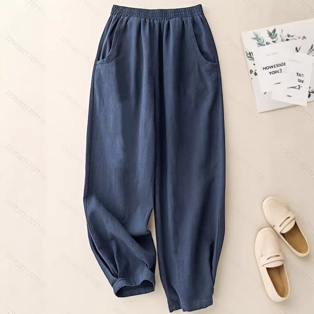 Blue pants on a beige surface with a book and slippers in the background