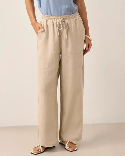 Person wearing beige wide-leg pants and a light blue top on a plain background