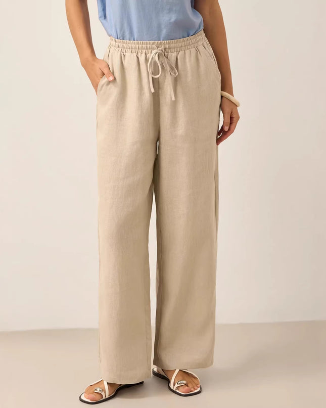 Person wearing beige wide-leg pants and a light blue top on a plain background