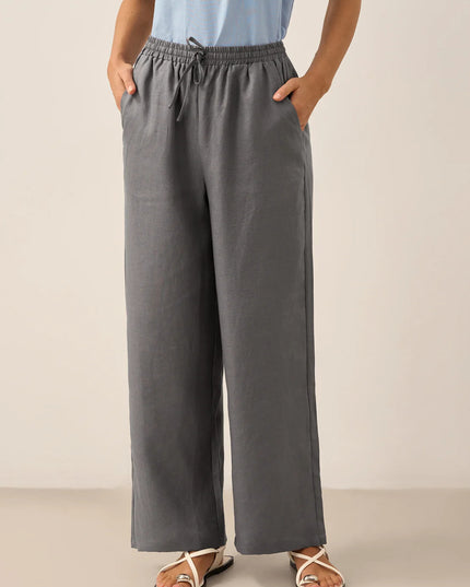 Person wearing gray wide-leg pants with a plain background