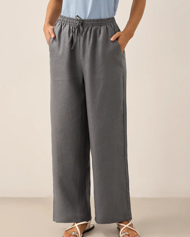 Person wearing gray wide-leg pants with a plain background