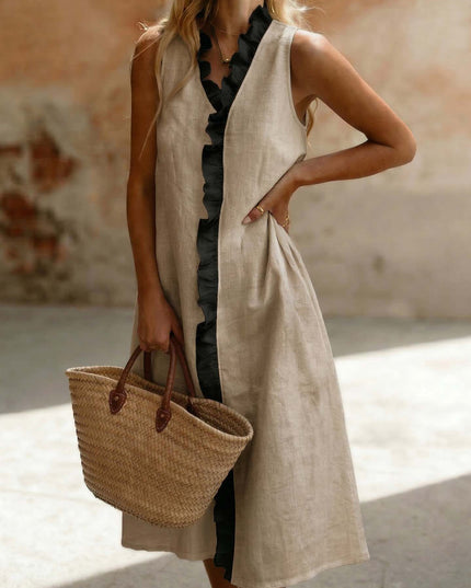 Woman wearing a sleeveless beige dress holding a straw bag.