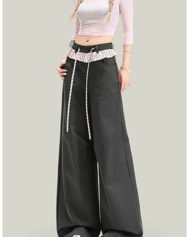 Person wearing a pink long-sleeve top and black wide-leg pants on a gray background