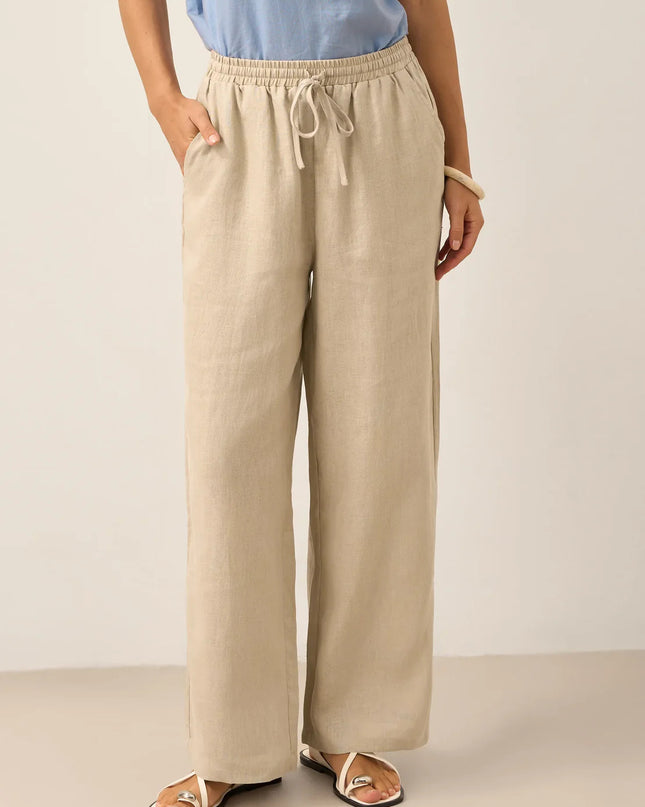 Person wearing beige wide-leg pants with a plain background