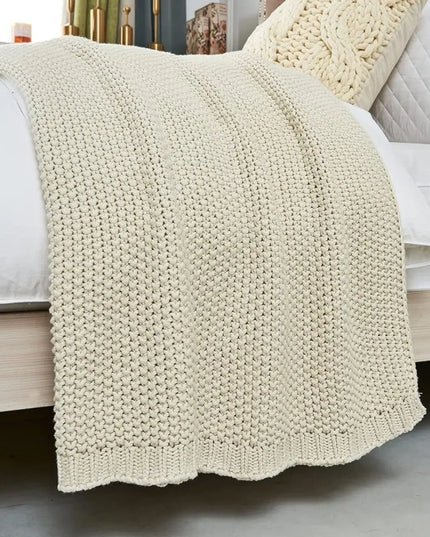 Beige chunky knitted blanked on a bed