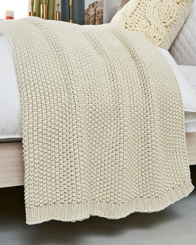 Beige chunky knitted blanked on a bed