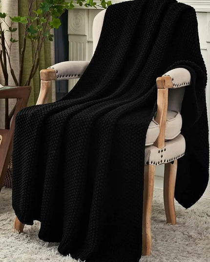 Black chunky knitted throw blanket on a chair