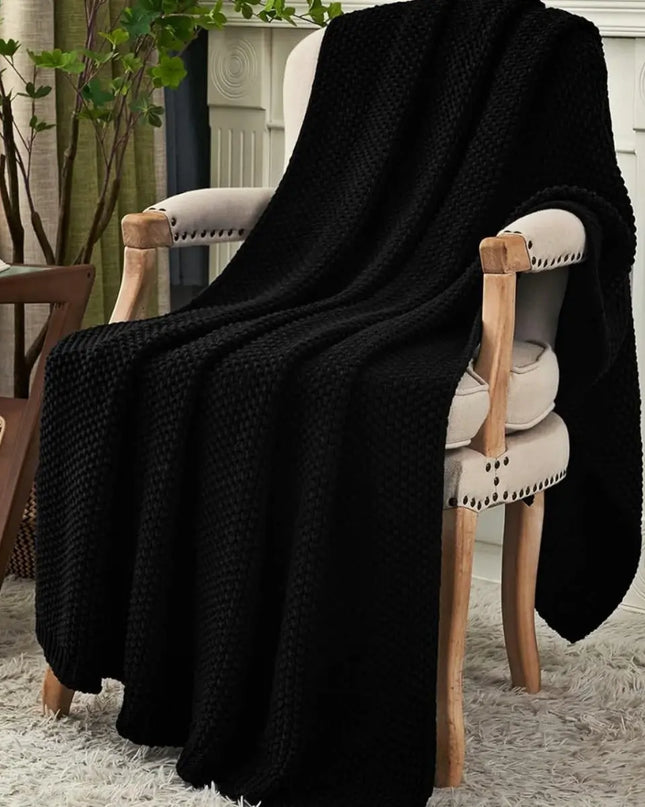 Black chunky knitted throw blanket on a chair