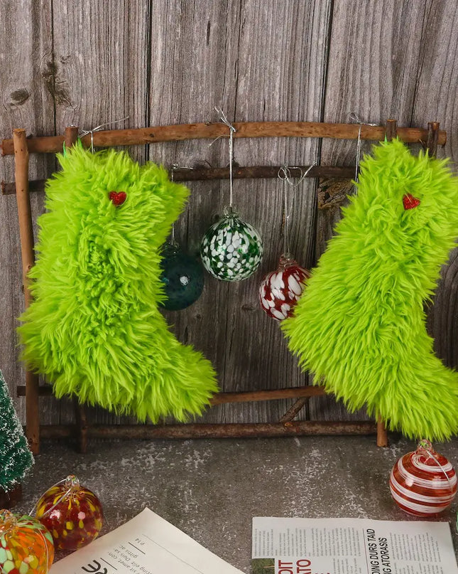 Two bright lime green fuzzy Christmas stockings hanging on a rustic wooden rack, surrounded by holiday ornaments and a weathered wood backdrop.
