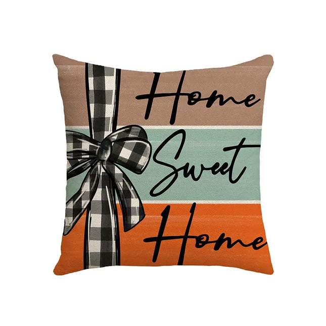 Decorative pillow with 'Home Sweet Home' text and plaid bow on a white background