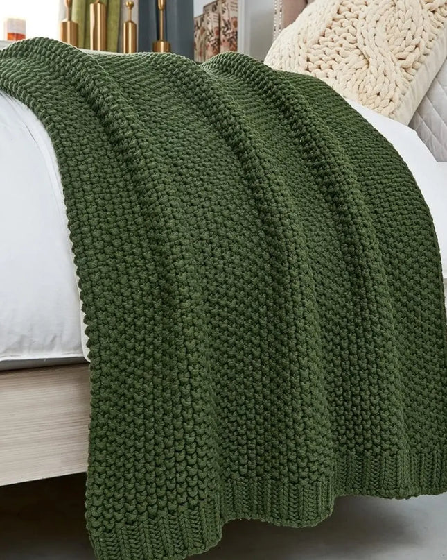 Green chunky knitted throw blanket on a bed
