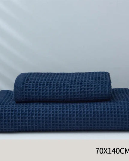 Two blue waffle-textured towels on a white surface with a light gray background.