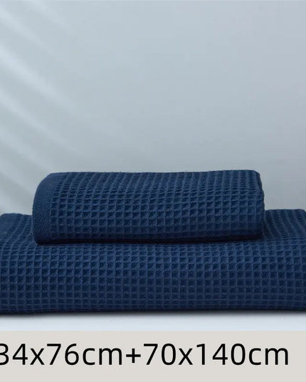 Two blue textured towels of different sizes on a white surface with a light gray background.