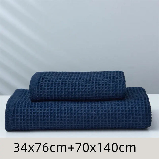 Two blue textured towels of different sizes on a white surface with a light gray background.