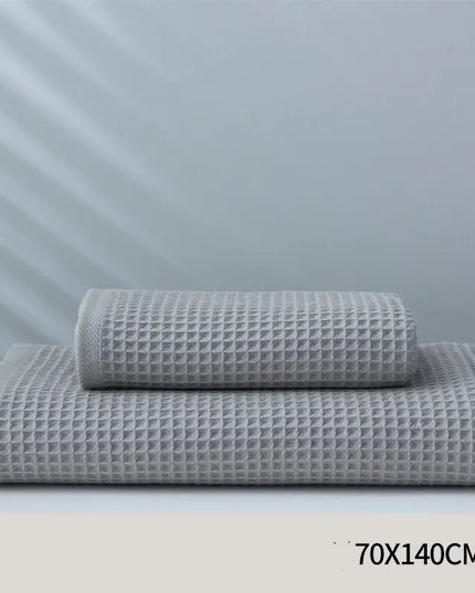 Two gray textured towels stacked on a white surface with a light gray background