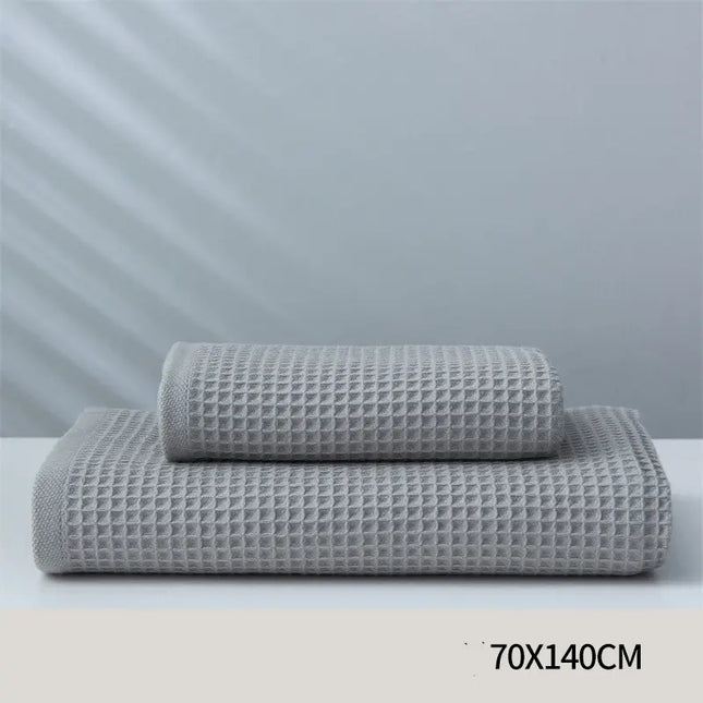 Two gray textured towels stacked on a white surface with a light gray background