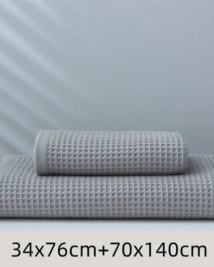Two gray textured towels stacked on a white surface with a light gray background.