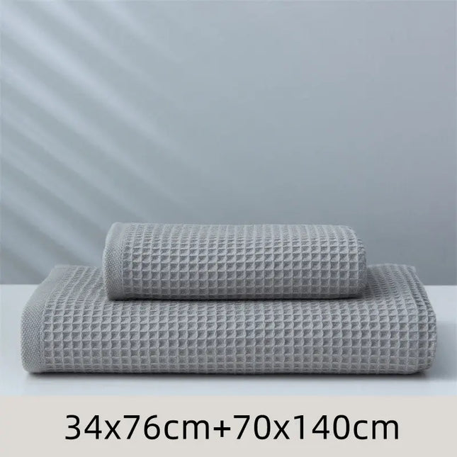 Two gray textured towels stacked on a white surface with a light gray background.