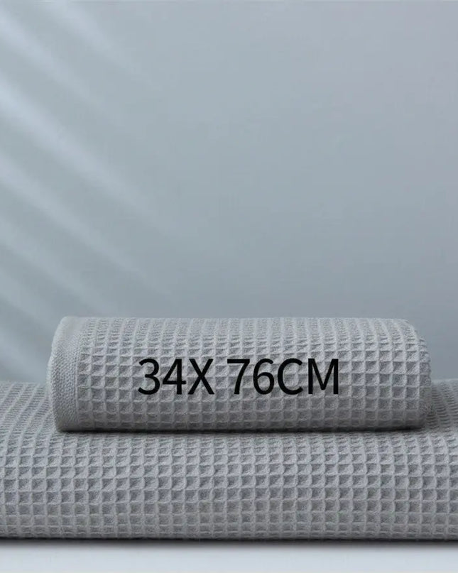 Two gray waffle-textured towels stacked on a white surface with measurement text '34X76CM' against a light gray background.