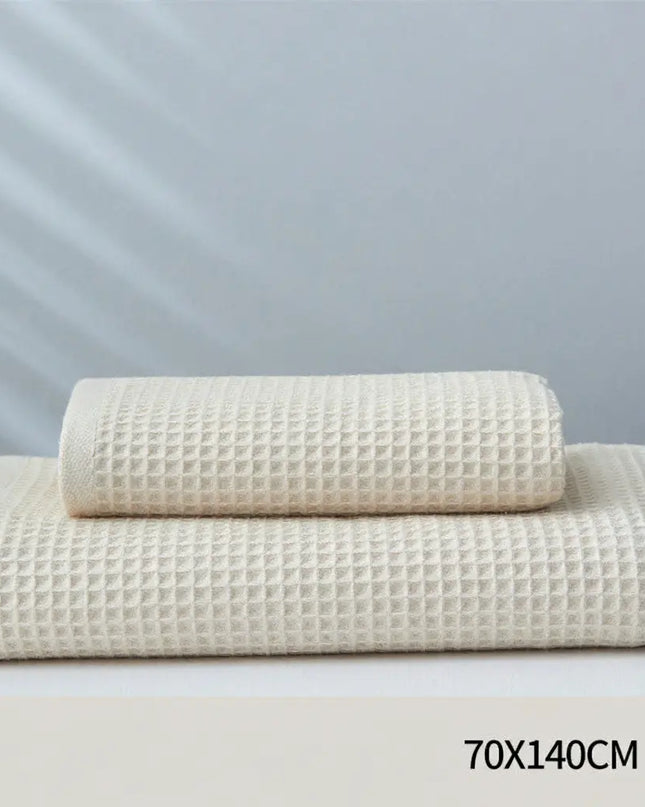 Two beige textured towels on a light gray background with size label '70X140CM'.