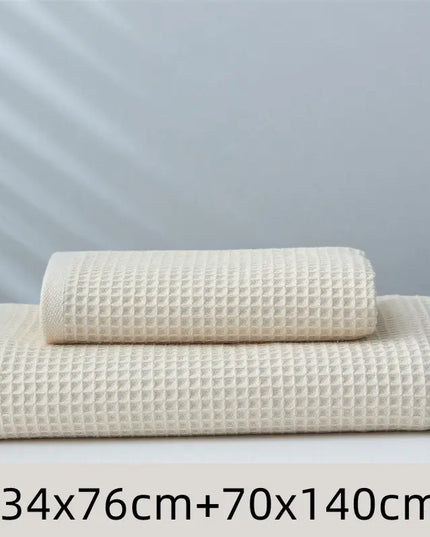Two beige textured towels of different sizes on a light gray background
