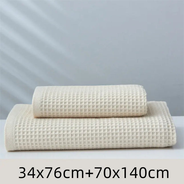 Two beige textured towels of different sizes on a light gray background
