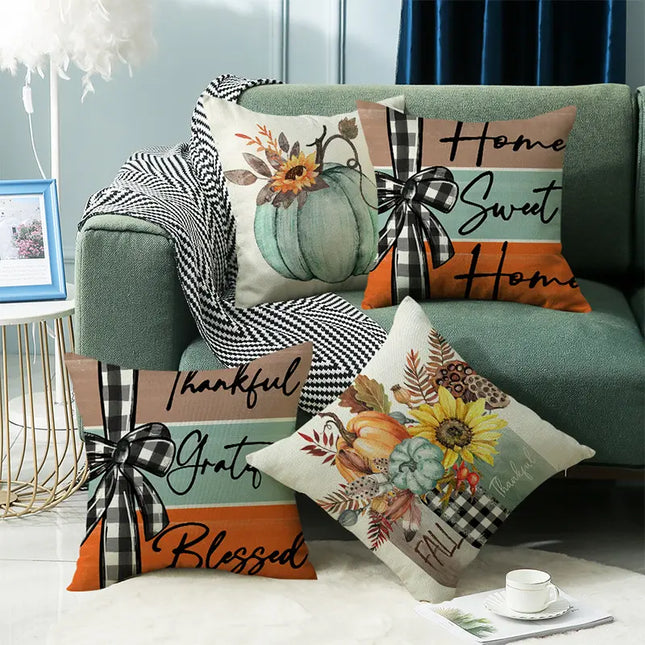 Four decorative throw pillows styled on a green sofa in a living room setting. The pillows feature a fall harvest theme with pumpkins, sunflowers, plaid bows, and autumn text including 'Home Sweet Home', 'Thankful Grateful Blessed', and 'FAEL'.