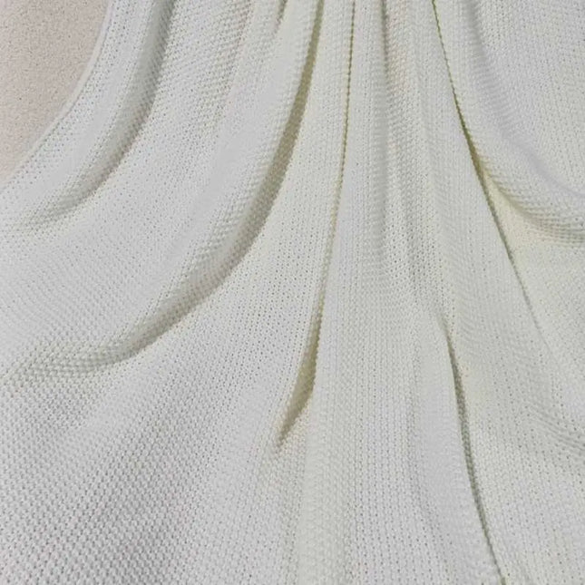 Close up picture of white knitted throw blanket