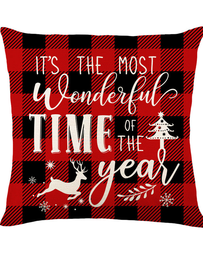 A square throw pillow featuring a red and black buffalo plaid pattern with white festive text reading 'IT'S THE MOST Wonderful TIME OF THE year' and holiday silhouettes including a deer, tree, and snowflakes, shown on a plain white background.
