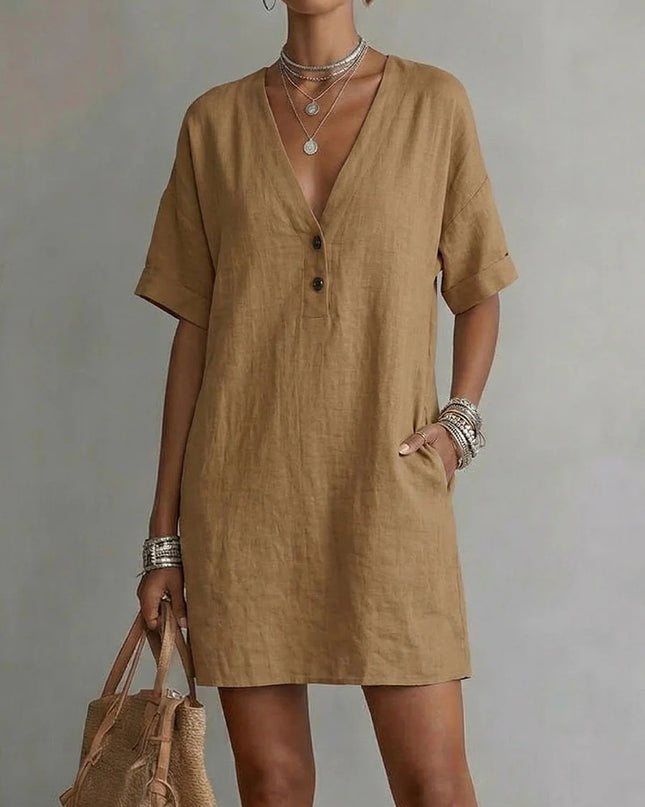 Woman wearing a brown dress holding a matching bag against a neutral background