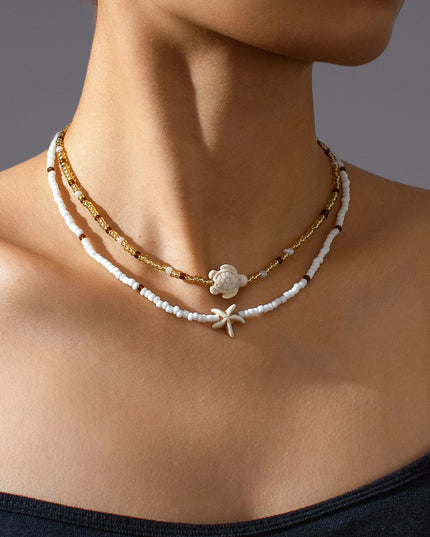 Close-up of a woman wearing a delicate necklace with a starfish pendant on a neutral background