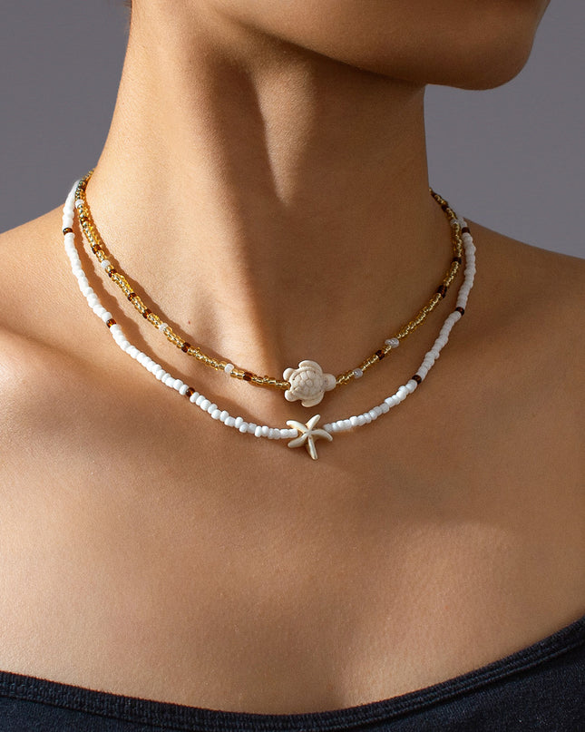 Close-up of a woman wearing a delicate necklace with a starfish pendant on a neutral background