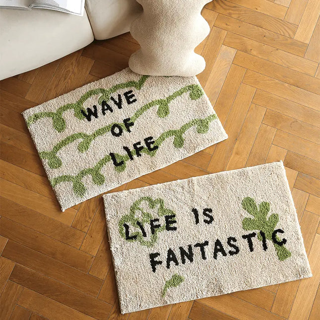 Two doormats on a wooden floor with motivational phrases.