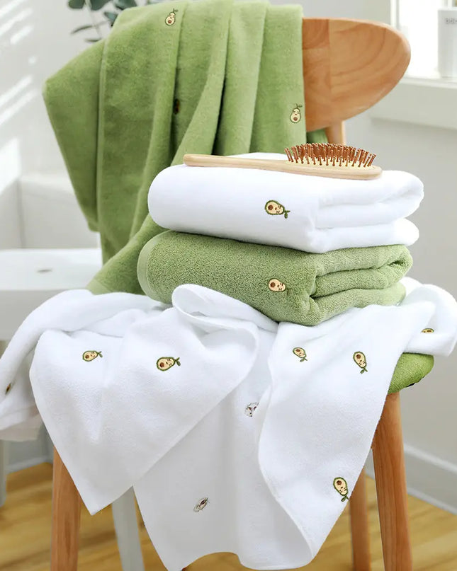Green and white baby towels with a comb on a wooden chair indoors.