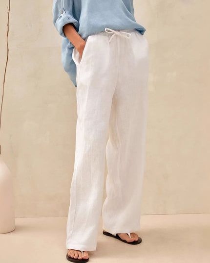 Person wearing white pants and a light blue shirt against a beige background