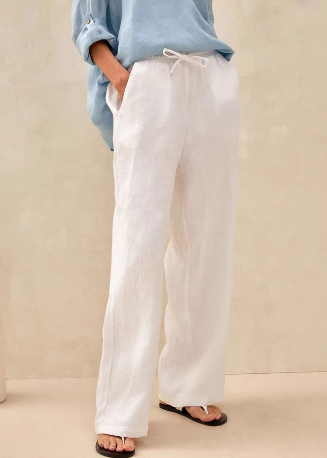 Person wearing white pants and a light blue shirt against a beige background